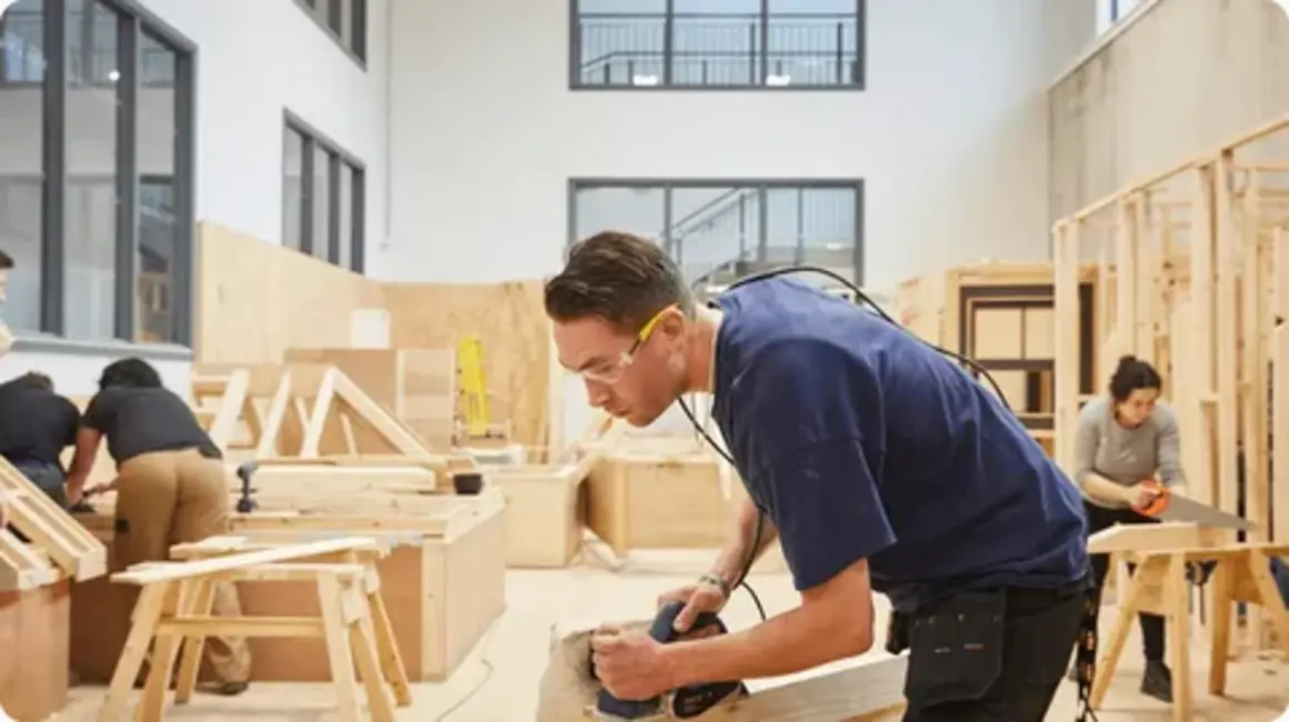 A construction professional examining blueprints inside a wooden house frame, representing professional carpentry services during residential construction.