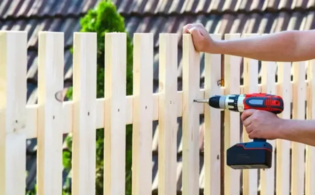 Wooden backyard fence being cleaned and inspected as part of regular fence maintenance