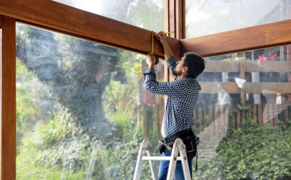 A professional carpenter is repairing a wooden window frame