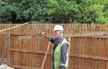 Professional construction worker moving fencing