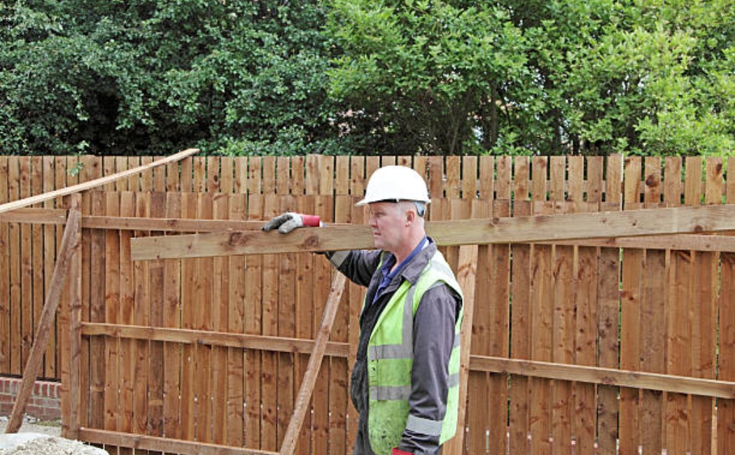Professional construction worker moving fencing