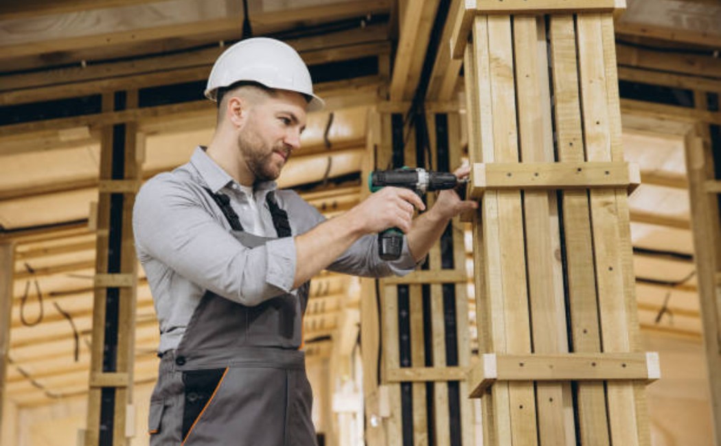 construction worker using cordless drill on wooden frame site