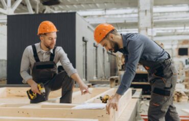 Construction workers building a wooden frame inside a factory