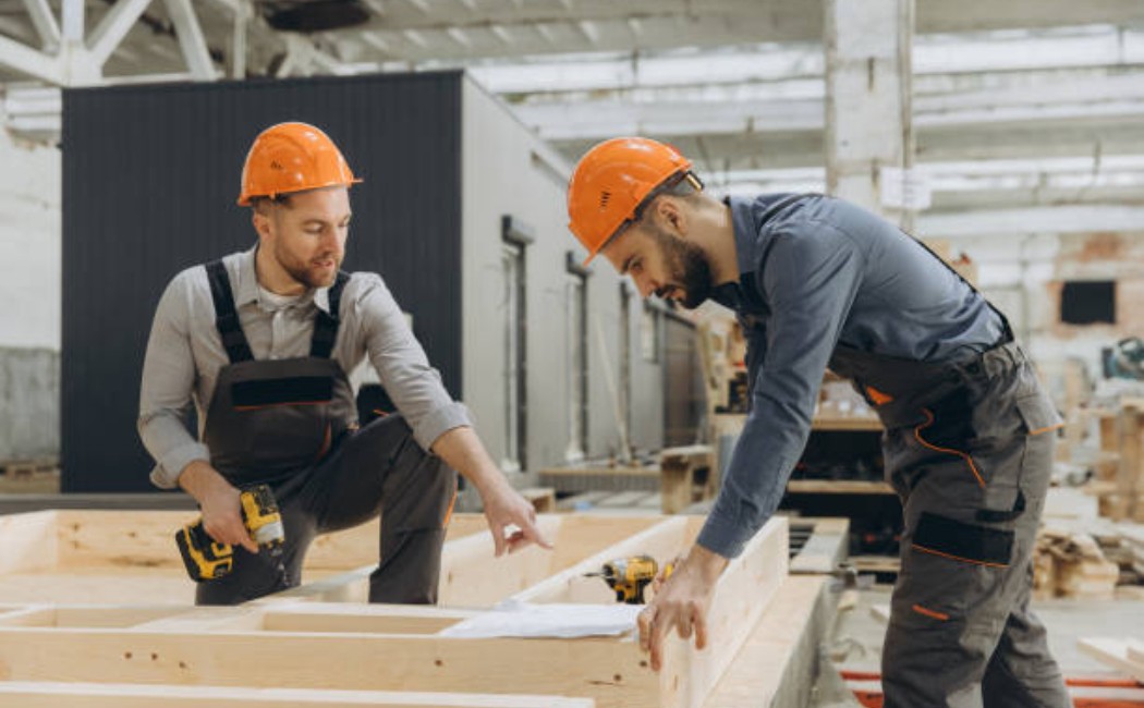 Construction workers building a wooden frame inside a factory
