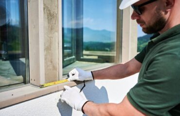 Construction worker measuring a window frame before installation.