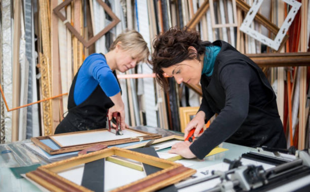 Two women restoring picture frames in a workshop lab area
