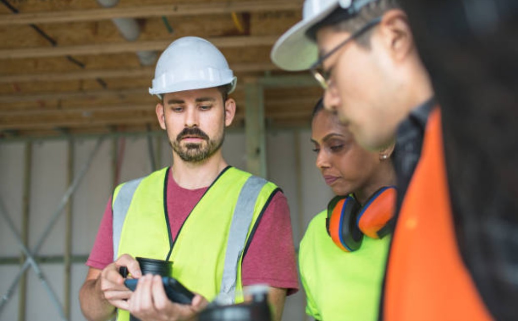 Construction workers reviewing project details on a mobile phone during a break. 