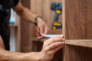 Professional carpenter measuring a custom wooden wardrobe for accurate installation and carpentry work.