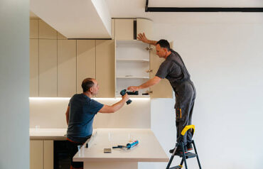 Professional carpenters installing upper kitchen cabinets as part of a custom carpentry service.