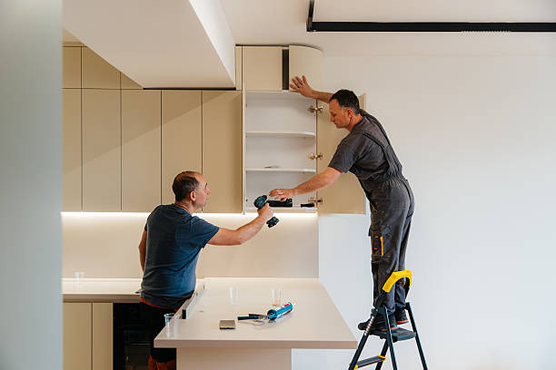 Professional carpenters installing upper kitchen cabinets as part of a custom carpentry service.