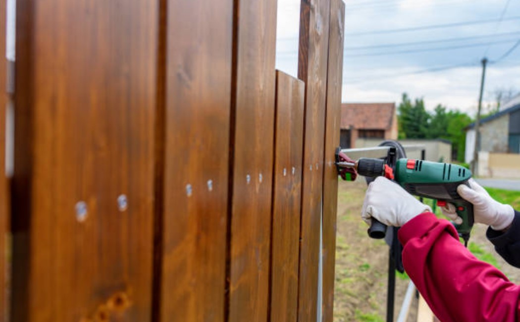 Worker building a custom wooden fence in a residential backyard