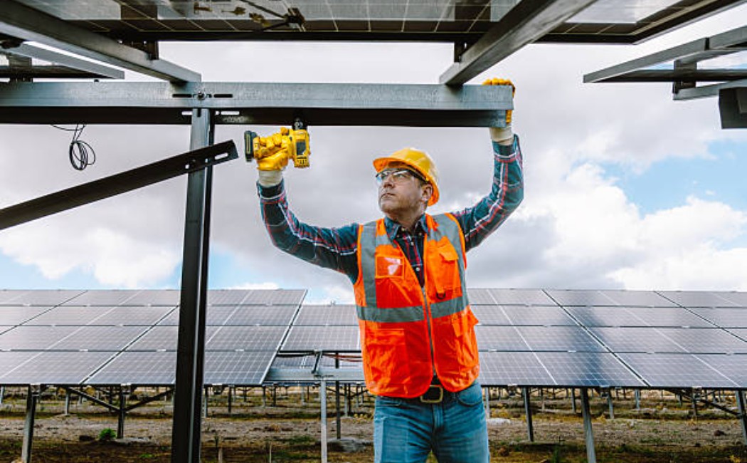 Construction worker building a metal fence using a cordless drill.